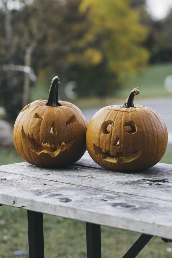 Halloween marketing image of two carved pumpkins, one with a cheerful face and another scary